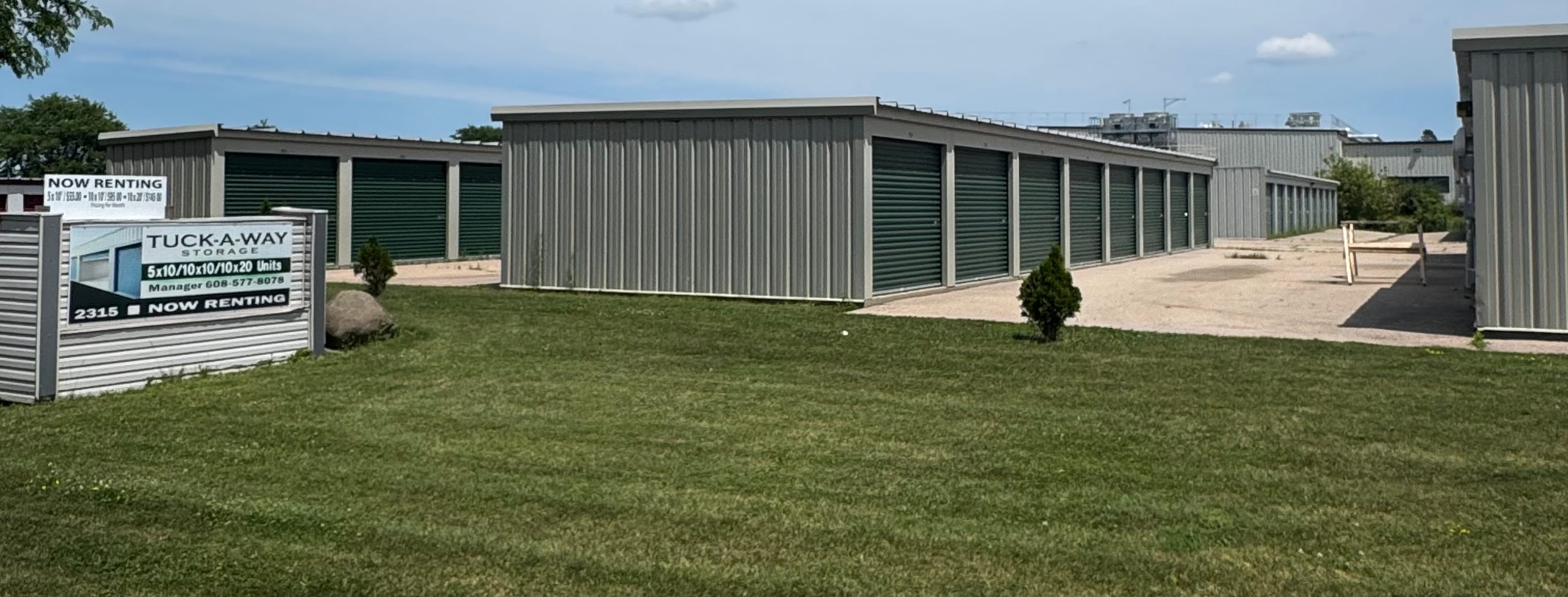 Wide exterior view of Tuck-A-Way Storage facility in Middleton, Wisconsin, showing rows of green roll-up door units on a sunny day
