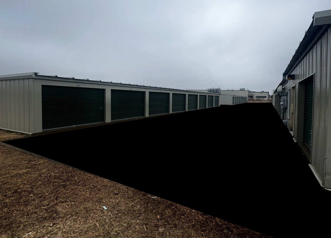 Rows of drive-up storage units with green roll-up doors at Tuck-A-Way Storage